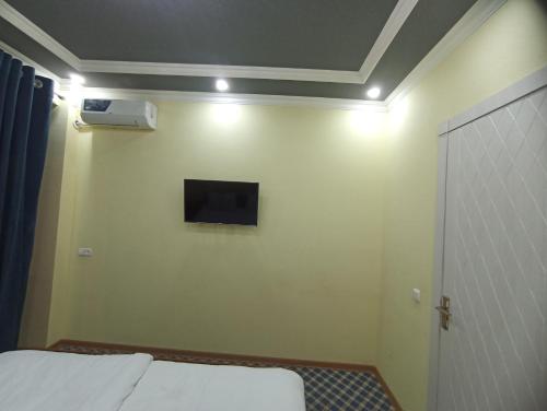 a bedroom with a bed and a tv on the wall at Shaxlo&Ali Hotels in Samarkand