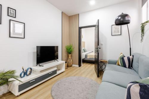 a living room with a tv and a blue couch at Cosy appartement met tuin in centrum Antwerpen Gratis parking Free Parking! in Antwerp