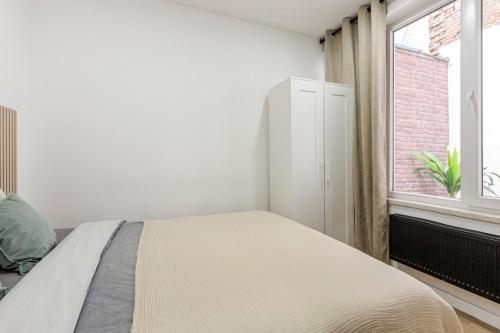 a white bedroom with a bed and a window at Cosy appartement met tuin in centrum Antwerpen Gratis parking Free Parking! in Antwerp