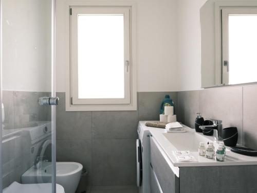 a bathroom with a sink and a toilet and a window at La Rocca - terrazza panoramica in Darfo