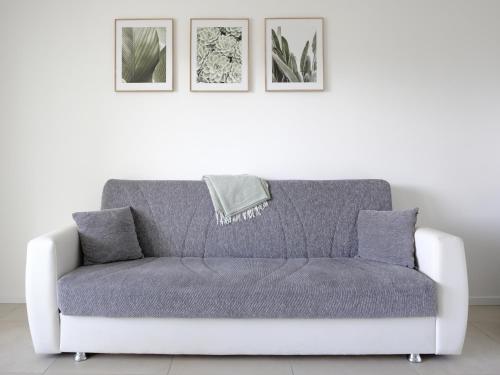 a couch in a living room with three pictures at La Rocca - terrazza panoramica in Darfo
