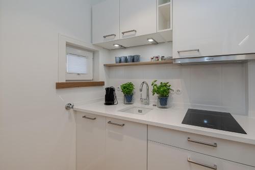 a white kitchen with white cabinets and a sink at Kleine Perle in Kampen