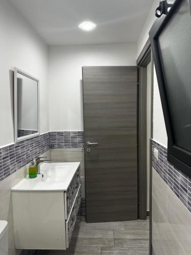 a bathroom with a sink and a wooden door at Mary House Apartments in Catania
