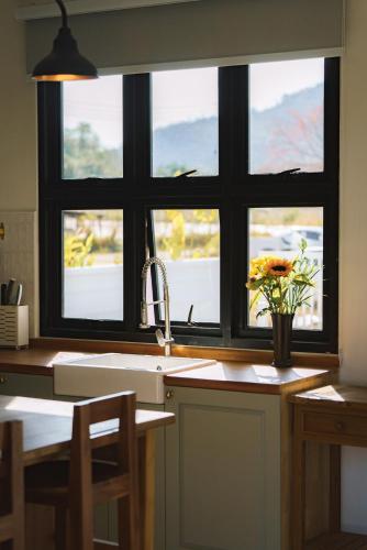 a kitchen with a sink and a window with a vase of flowers at Queenstown Khaoyai in Pak Chong