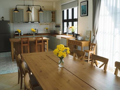 a kitchen with a wooden table with yellow flowers on it at Queenstown Khaoyai in Pak Chong
