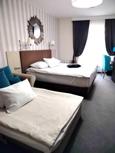 a hotel room with two beds and a mirror at Hotel Sokołowska Airport Modlin in Nowy Dwór Mazowiecki