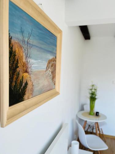 a painting hanging on a wall next to a table at Dom na wzgórzu z widokiem na jezioro in Brodnica Dolna
