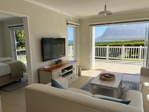 a living room with a couch and a tv and a balcony at Views galore in Kleinmond in Kleinmond