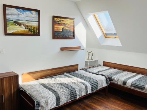 a bedroom with two beds and paintings on the wall at Dom na wzgórzu z widokiem na jezioro in Brodnica Dolna