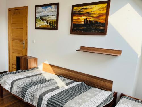 a bedroom with a bed and two pictures on the wall at Dom na wzgórzu z widokiem na jezioro in Brodnica Dolna