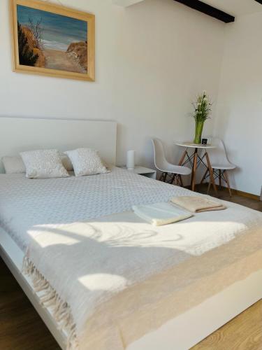 a large white bed in a room with a table at Dom na wzgórzu z widokiem na jezioro in Brodnica Dolna