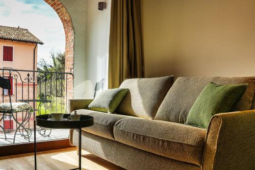 a couch with green pillows in a living room at Villa Clementina - Prosecco Country Hotel in San Pietro di Feletto
