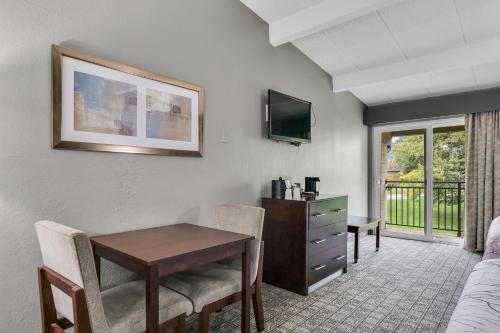a hotel room with a desk and a table with chairs at Eastlake Suites Hotel & Conference Center By OYO Urbana in Champaign