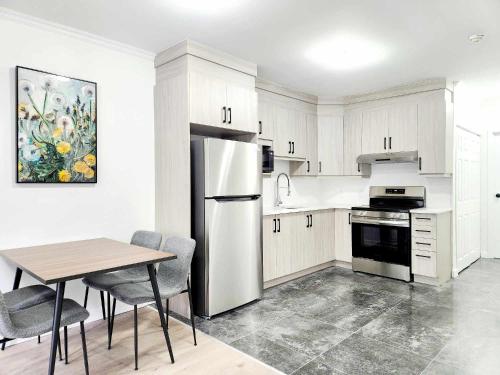 a white kitchen with a table and a refrigerator at APARTMENT HOTEL ST-DENIS in Montréal