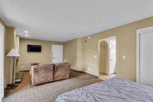 a bedroom with a bed and a couch and a tv at Eastlake Suites Hotel & Conference Center By OYO Urbana in Champaign
