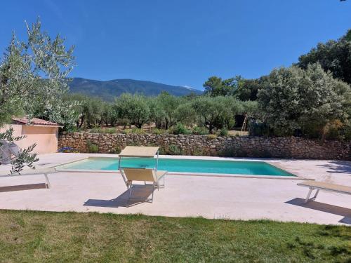 une piscine avec deux chaises et une table dans l'établissement Villa les Oliviers, à Bédoin