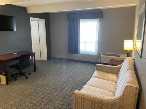 a living room with a couch and a desk and a window at Eastlake Suites Hotel & Conference Center By OYO Urbana in Champaign