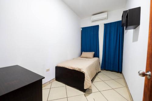 a small bedroom with a bed and blue curtains at Villa Tropical By Vacation Pura Vida in Esterillos Este