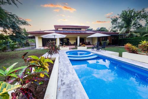 a swimming pool in front of a house at Villa Tropical By Vacation Pura Vida in Esterillos Este