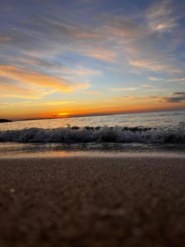 a sunset on the beach with the ocean at Cabaña MARDELA Casa de Playa in San Antero