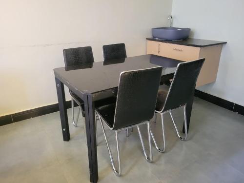a black table with four chairs in a room at Biira Transit Residence Entebbe with free airport pickup in Entebbe