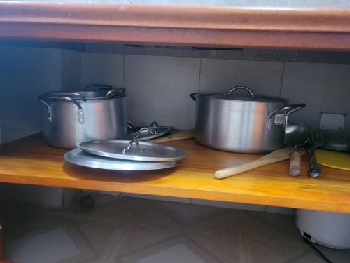 three pots and pans sitting on a wooden shelf at Biira Transit Residence Entebbe with free airport pickup in Entebbe