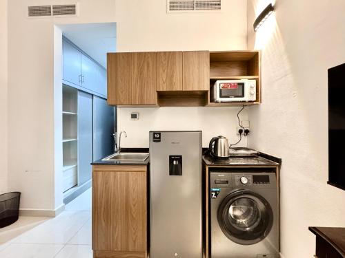 a kitchen with a washing machine and a microwave at Al Manara Classic Cozy Studio in Dubai