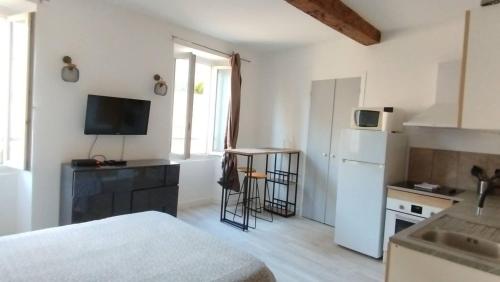 Elle comprend une petite cuisine équipée d'un réfrigérateur blanc et d'une table. dans l'établissement studio cosy centre ville, à Ajaccio
