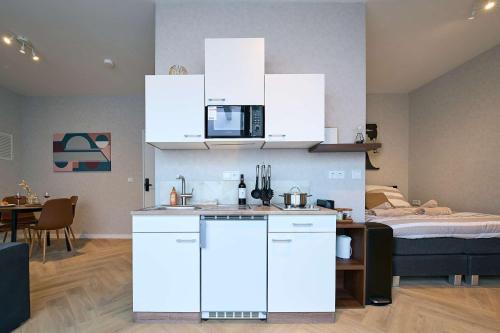 a kitchen with white cabinets and a bed in a room at Central City Escape Modern Studio Near Everything in Eindhoven