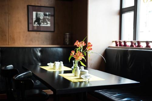 a black table with yellow napkins and a vase of flowers on it at Hotel Deutsches Theater Stadtzentrum in Munich