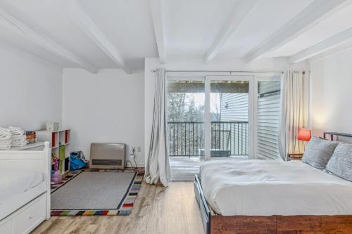 a white bedroom with a bed and a large window at Steps to Ski Trail Fireplace - Kingswood 1B in Quechee