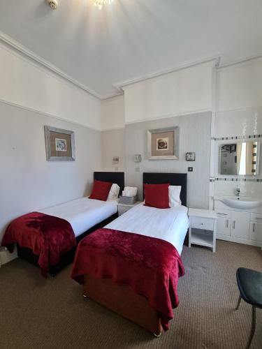 two beds in a hotel room with a sink at Clifton Villa - Southport in Southport