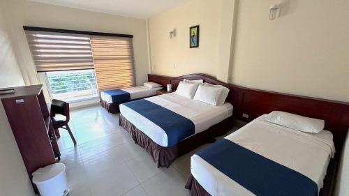 a hotel room with two beds and a window at Hotel Los Puentes Comfacundi in Girardot