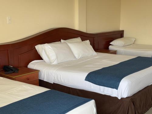 a hotel room with two beds with white and blue sheets at Hotel Los Puentes Comfacundi in Girardot
