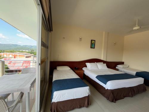 a hotel room with two beds and a balcony at Hotel Los Puentes Comfacundi in Girardot