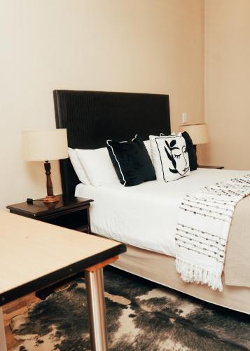 a bedroom with a bed with black and white pillows at Letona Guesthouse in Kuruman