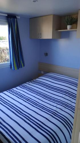 a bedroom with a blue and white striped bed with a window at Mobil-home camping 4 étoiles cancale in Cancale