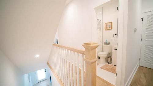 a white bathroom with a staircase and a toilet at Stylish 4BR Home Near Columbia Heights & Rooftop in Washington, D.C.