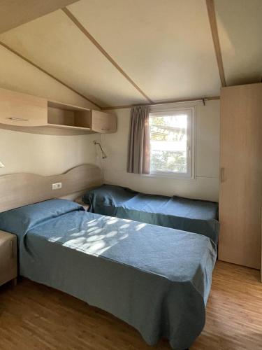 two beds in a small room with a window at Camping Smeraldo in Trevignano Romano