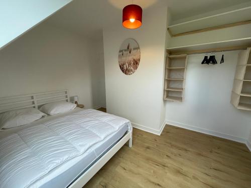 a bedroom with a white bed and a lamp at Ty Plom proche du centre et des plages in Plomeur