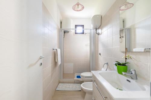 Un baño blanco con lavabo e inodoro. en Casa Paola, en Tortolì