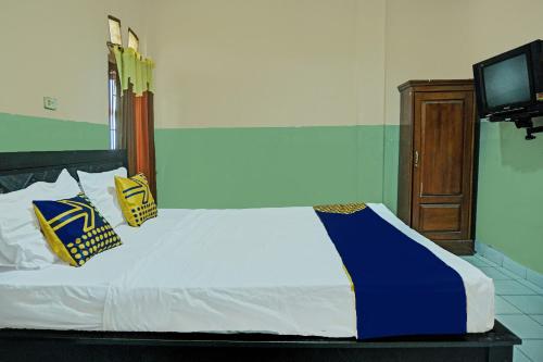 a bed with blue and white sheets and a television at Hotel O Romli in Rumpuktulunghoni