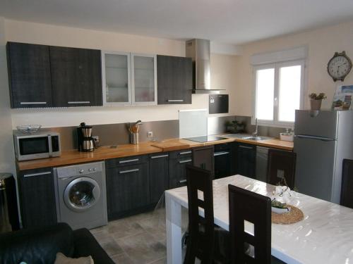 une cuisine avec des armoires noires et un lave-linge/sèche-linge dans l'établissement Gîte les Onagres 2 Le Crotoy, à 2 minutes de la plage, au Crotoy