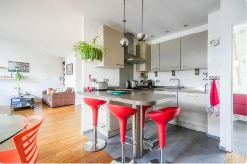 une cuisine avec tabourets de bar rouge et table dans l'établissement Sweet home, à Paris