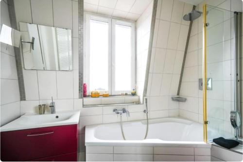 une salle de bain avec une baignoire, un lavabo et une fenêtre dans l'établissement Sweet home, à Paris