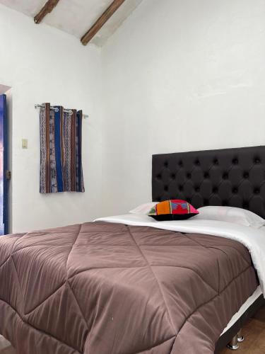 a large bed with a brown headboard in a room at Auquis Hostel in Cusco