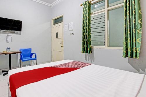 a bedroom with a bed and a desk and a window at OYO 92287 Hotel Aji Mantoro in Wonogiri