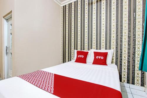 a red and white bed with two red pillows on it at OYO 92287 Hotel Aji Mantoro in Wonogiri