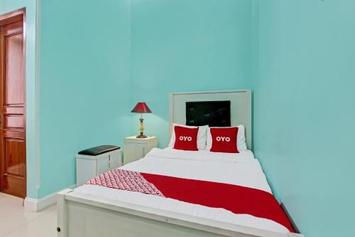 a bedroom with a bed with two red pillows at Hotel O Amole Homestay Syariah in Cilacap