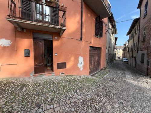 an alley with an orange building on a street at Leila's House Fontane Del Duca in CastellʼArquato
